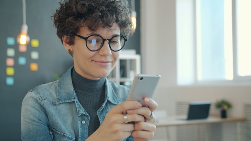 Pessoa sorrindo enquanto usa o celular